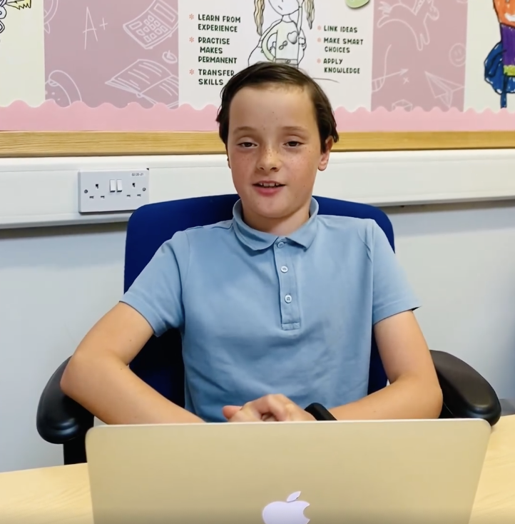Laxey school pupil Ivy sat at a desk with a MacBook